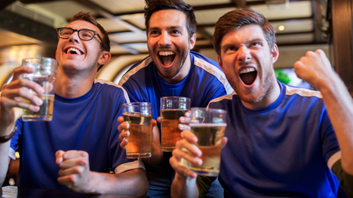 Football fans wearing blue and holding drinks