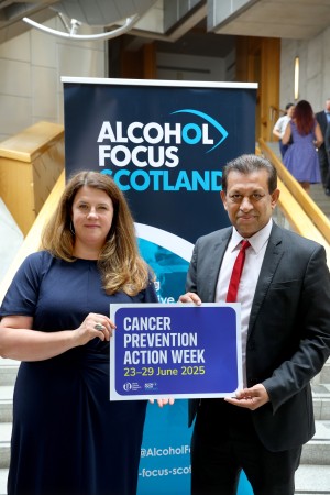 An image featuring Laura Mahon, Deputy CEO, with Foysol Choudhury MSP, holding a sign on Cancer Prevention Action Week