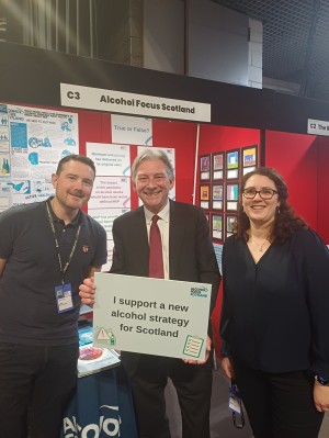 Image depicting AFS staff with MSP Richard Leonard, holding a sign calling for a new Alcohol Strategy