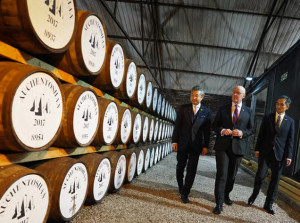 Image of the First Minister examining Whisky barrels on a tour.